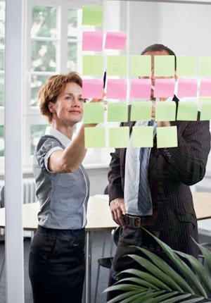 img-people-discussing-in-front-of-glass-with-sticky-notes-01-variation-01